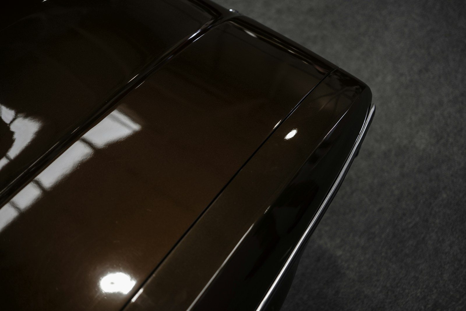 Cận cảnh nắp capo màu nâu bóng loáng phản chiếu ánh sáng