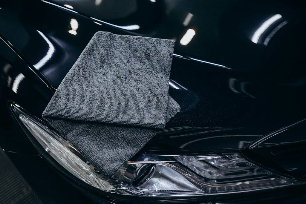 Khăn microfiber màu xám đặt trên nắp capo xe màu đen