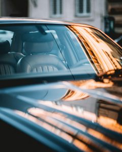 Cửa kính bên của một chiếc xe tối màu phản chiếu ánh đèn cam